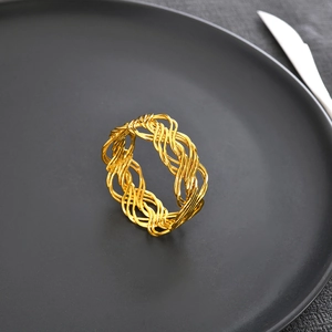 Elegant gold woven napkin ring on a minimalist black dinner plate for luxury table decor