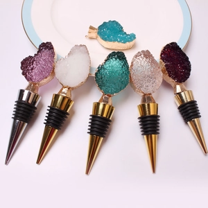 Set of crystal wine stoppers in various colors with metallic bases on a white plate