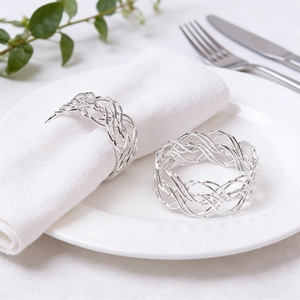 Elegant silver woven hollow napkin rings set on white ceramic plate with table decor