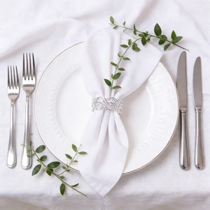 Close-up of silver woven napkin ring with hollow design on a white dinner napkin
