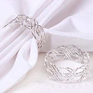 Detail of silver woven napkin rings featuring a hollow metal design on white cloth