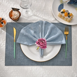 Blue-grey cotton linen placemat with pink rose napkin ring and gold cutlery on table