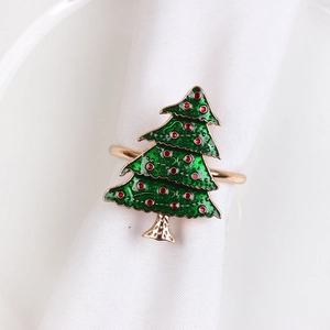 Detail of Christmas tree napkin ring with green enamel and red beads on white cloth