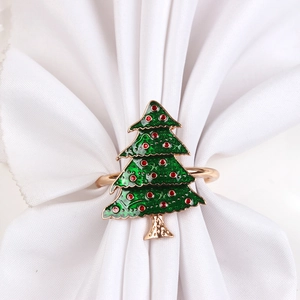 Detail of green enamel Christmas tree napkin ring with red rhinestones on white cloth