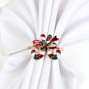 Close-up of Christmas candy cane napkin ring with red bow and rhinestone on white napkin