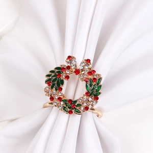 Detailed view of a golden Christmas wreath napkin ring with green leaves and red rhinestones