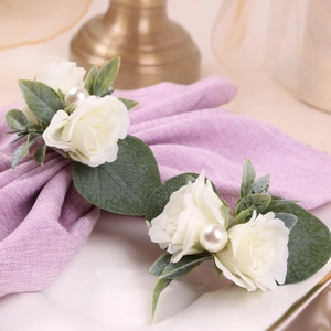 Détail d'un rond de serviette fait main avec rose blanche en soie, feuilles et perle