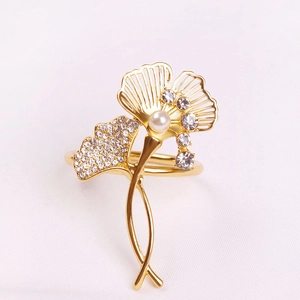 Elegant gold ginkgo leaf napkin ring with pearls and rhinestones on white fabric