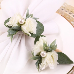 Rond de serviette rose blanche avec feuilles vertes et perle sur nappe blanche