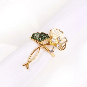 Ginkgo leaf napkin ring with green crystals and pearl on white cloth napkin