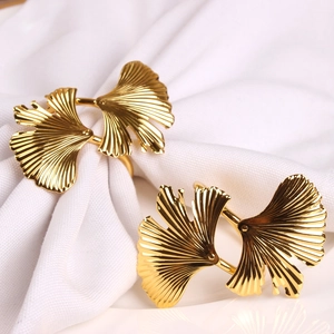 Set of two gold ginkgo leaf napkin rings with detailed leaf veins on white fabric
