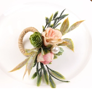 Faux double rose and pine cone napkin ring on a white ceramic plate for table decor
