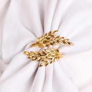 Macro detail of golden leaf napkin ring showing intricate veins on white linen
