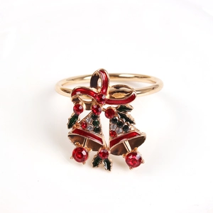Detail of Christmas napkin ring featuring gold bells, red bow, and crystal holly leaves