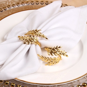 Detail shot of golden leaf napkin rings on white linens for luxury table settings