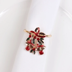 Detail of Christmas napkin ring with golden bells and red bow on white napkin