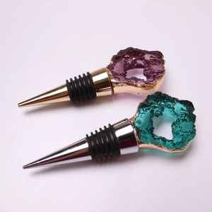 Detailed view of two wine stoppers with purple and teal crystals and gold-edged plating