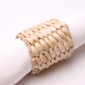 Close-up of hand-woven water hyacinth napkin ring on a white cloth for table decor