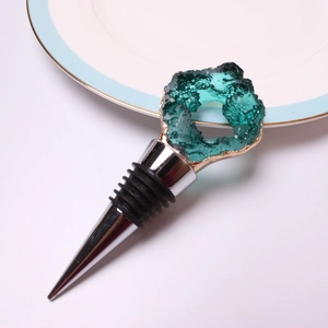Close-up of green crystal wine stopper with gold edge and stainless steel base