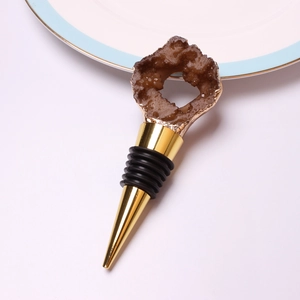 Natural brown crystal wine stopper with gold-plated edges and rubber seals on white background