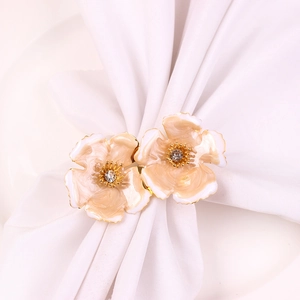 Macro detail of champagne enamel flower napkin rings with gold edges and crystal center
