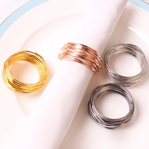 Macro view of four-color spiral metal napkin rings on a ceramic plate for table decor