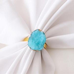 Close-up of a blue geode agate napkin ring with gold foil edges on a white cloth