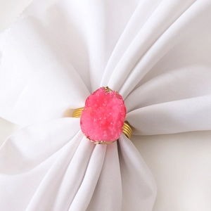Detailed close-up of a pink quartz napkin ring with gold plating on a white napkin