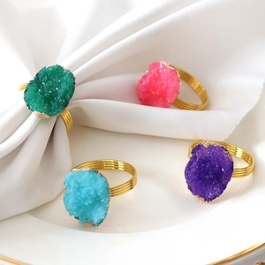 Detail of colorful druzy stone napkin rings with gold wire base on a white dinner plate