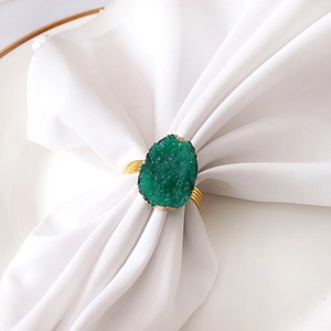 Macro view of gold spiral wire napkin ring with a natural green crystal cluster stone