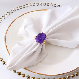 Detail of purple agate napkin ring on white linen napkin with gold decorative rim