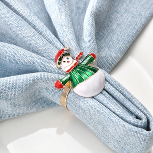 Détail d'un rond de serviette bonhomme de neige en émail sur tissu bleu et assiette blanche