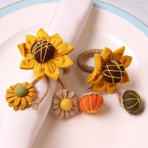 Pair of sunflower napkin rings with pumpkin accents and autumn elements on white plates