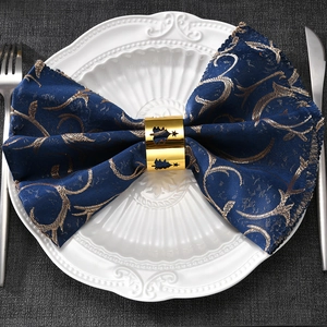 Golden Christmas tree metal napkin ring with hollow star design on blue fabric