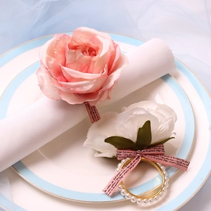 Detail of pink silk rose and white camellia napkin rings with pearls and ribbons