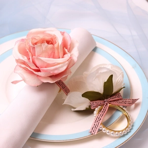 Detail of pink rose napkin ring with white pearls and golden band for wedding decor