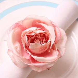 Close-up of pink fabric rose napkin ring on white napkin for elegant table decor