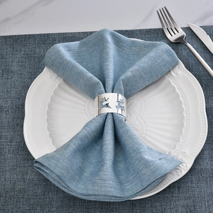 Polished silver metal reindeer napkin ring on blue linen napkin for Christmas table decor