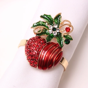 Detail of Christmas napkin ring featuring red holly berries and green enamel leaves
