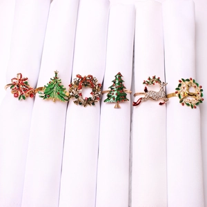Detail view of various Christmas napkin rings with reindeer and tree motifs on white napkins