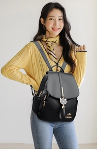 Detail of black soft leather backpack featuring gold kangaroo logo and cat pendant charm
