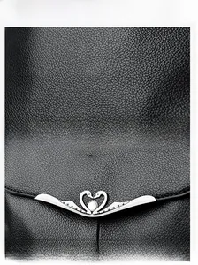 Close-up of black lychee grain leather texture and swan-shaped metal hardware logo