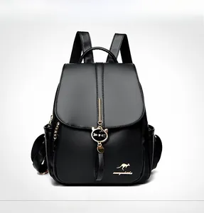 Detailed view of black litchi pattern leather backpack with golden kangaroo logo and cat charm