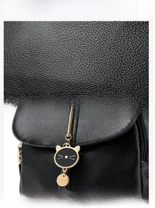 Detail of black pebbled leather texture and cute golden cat charm on fashion backpack