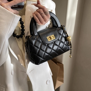 Classic black quilted leather handbag with gold twist lock and chain strap carried by hand