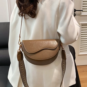 Vintage brown saddle bag with geometric wide strap shown on a model's shoulder