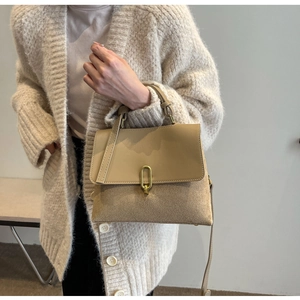Detail view of khaki crossbody bag with vintage gold clasp on stylish knit sweater