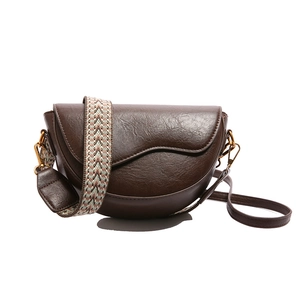 Deep brown faux leather saddle bag with woven strap and vintage gold hardware