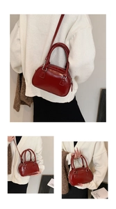 Detail of red glossy leather Boston bag with double handles and silver hardware
