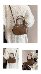 Detail view of a small brown leather Boston bag with handles and detachable shoulder strap